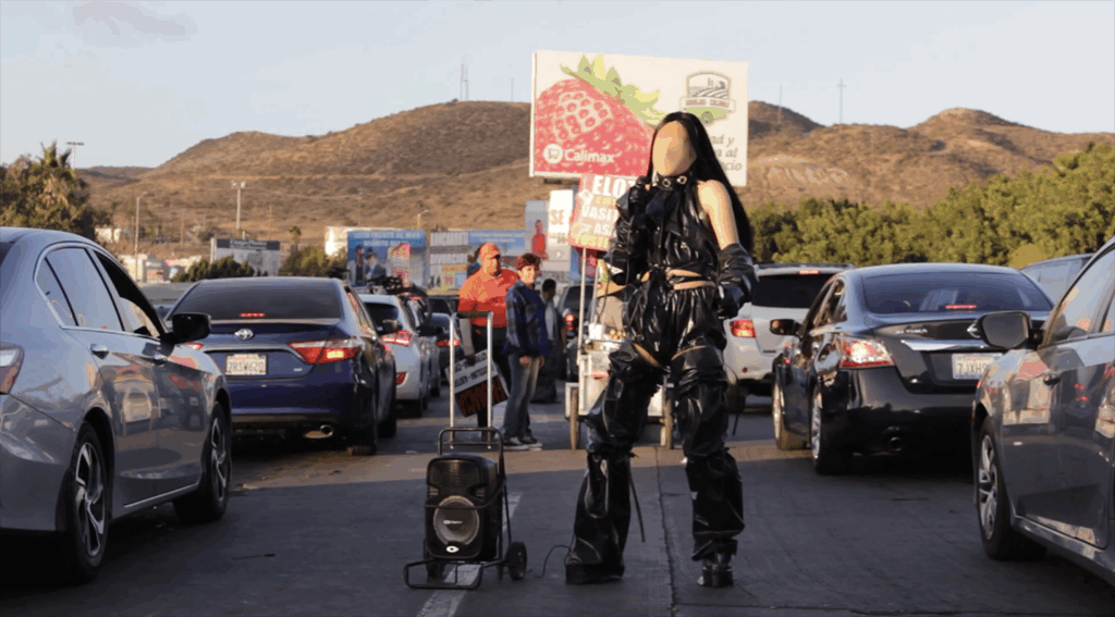 Faceless person wearing black in the middle of a road with traffic