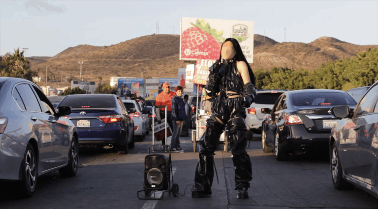 Faceless person wearing black in the middle of a road with traffic