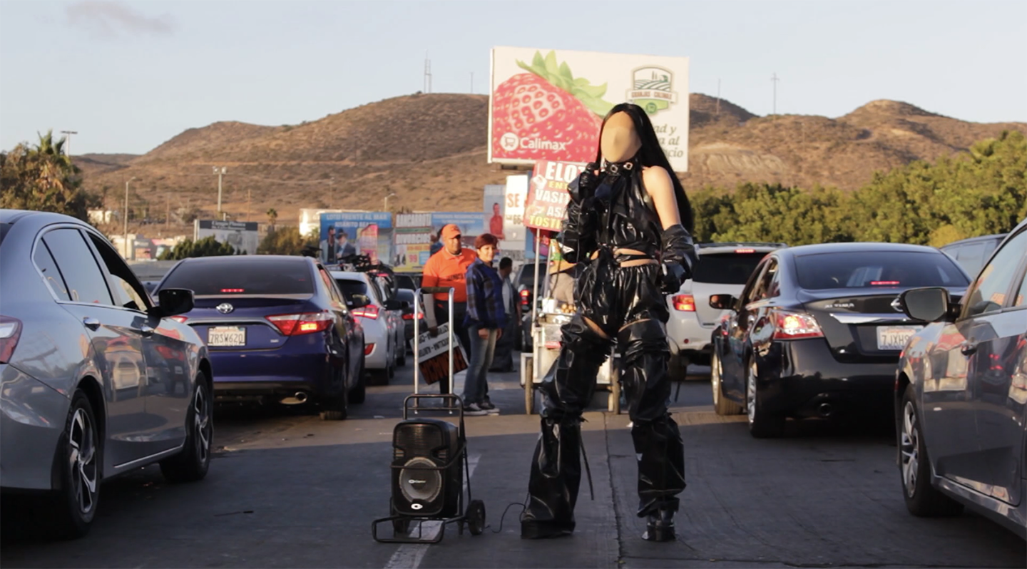 Faceless person wearing black in the middle of a road with traffic