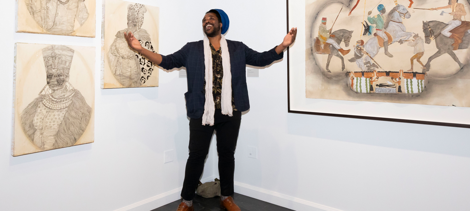 Man standing a corner of a room with artworks hanging on both sides of the wall.