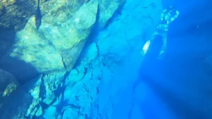 a film still showing an underwater scene and a person scuba diving