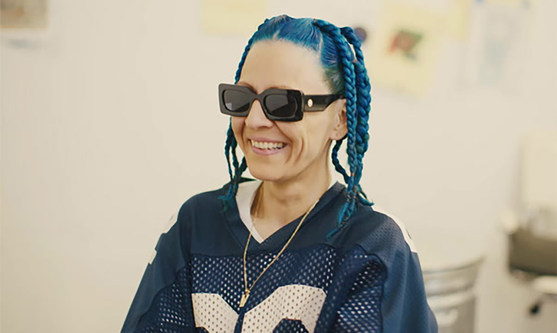Portrait of woman with blue braided hair wearing sunglasses and smiling off camera