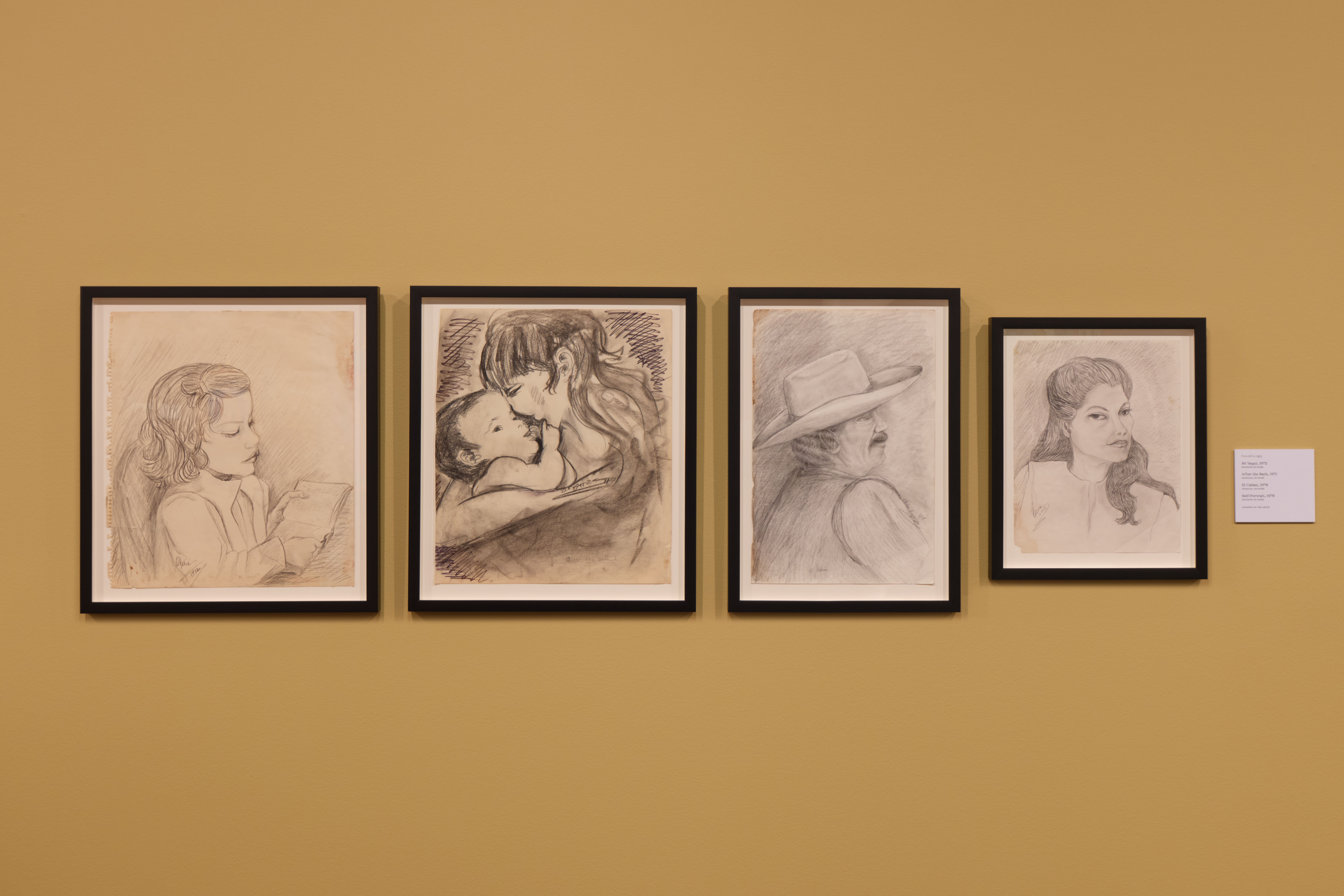 a photograph of a yellow wall with drawings in frames